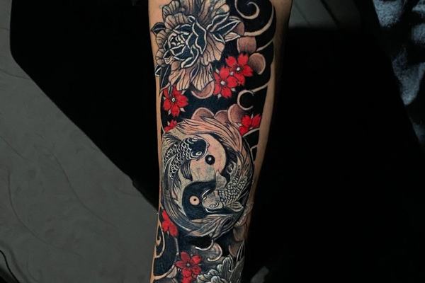 Koi fish forearm tattoo with flowers and dark shading