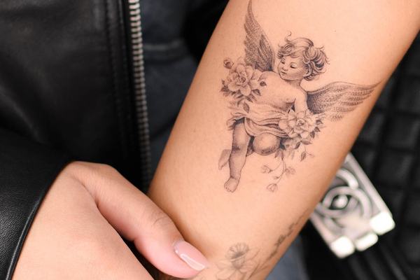 Small cherub angel tattoo with flowers
