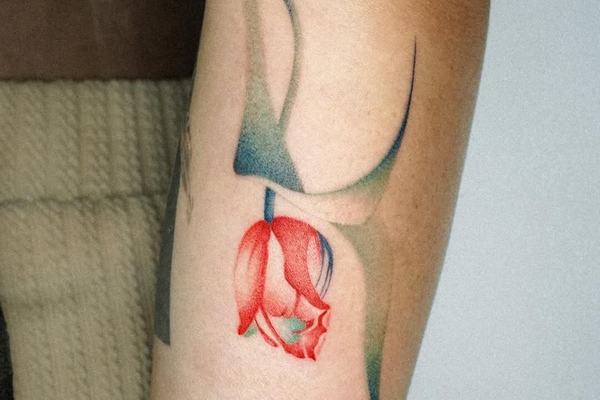Red tulip tattoo with soft abstract background
