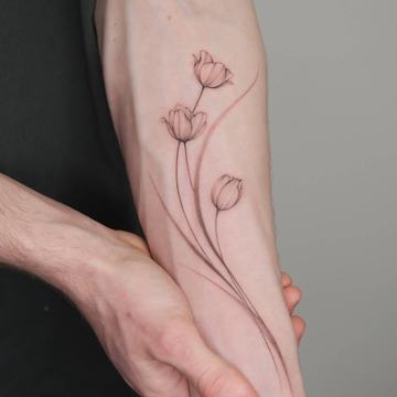 Minimal tulip tattoo with long stems on the forearm
