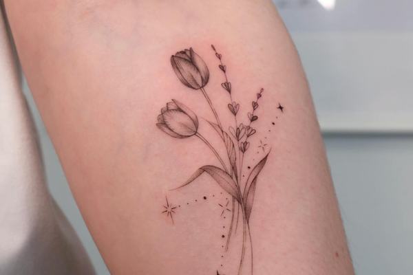 Fine line tulip tattoo with small decorative stars
