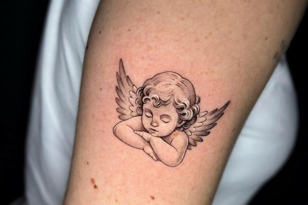Sleeping cherub angel tattoo on the arm
